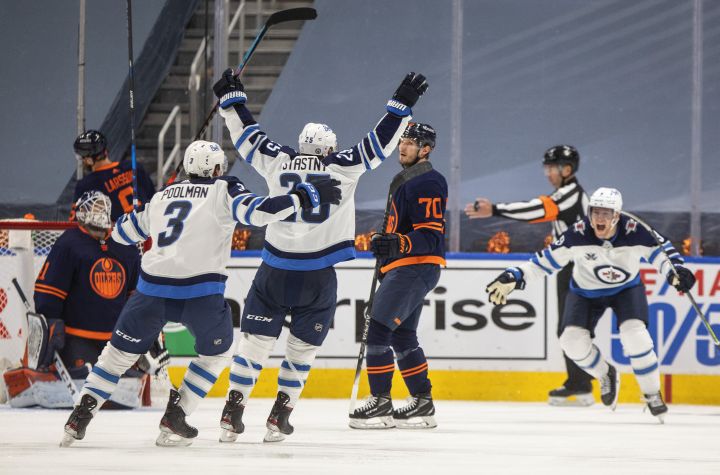 Edmonton Oilers goalie Mike Smith (41) and Ryan McLeod (70) look on as Winnipeg Jets’ Tucker Poolman (3) and Paul Stastny (25) celebrate a goal during overtime NHL Stanley Cup playoff action in Edmonton on Friday, May 21, 2021.