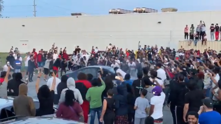 This car was seen doing doughnuts as a large crowd gathered around.