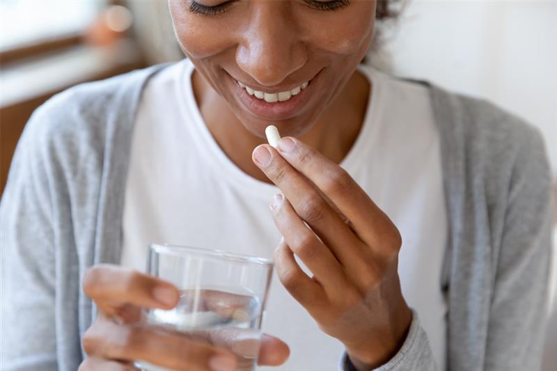 Woman taking probiotics with water.