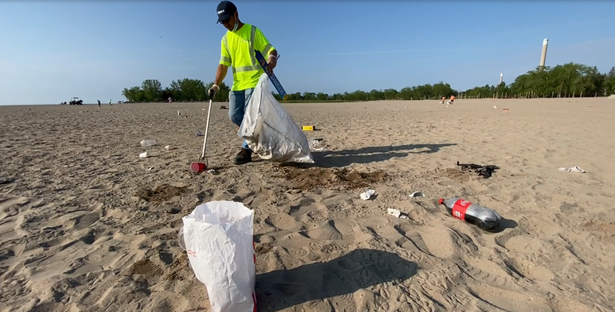 FILE. A city worker cleans up garbage left behind at Ashbridge's Bay beach.