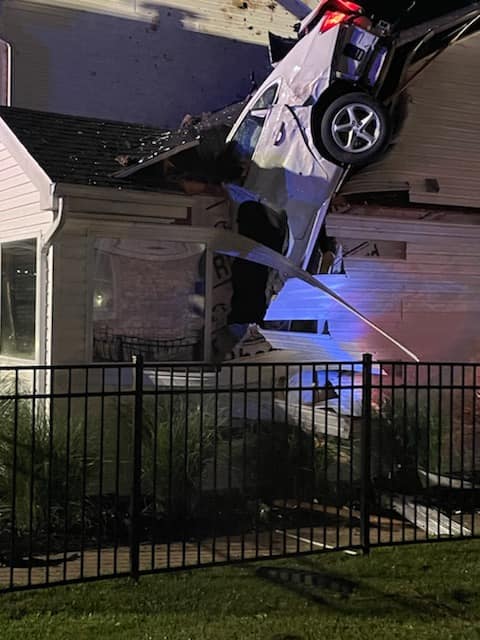 Crews work to remove a car from the roof of a home in Eureka, Missouri, on May 23, 2021.