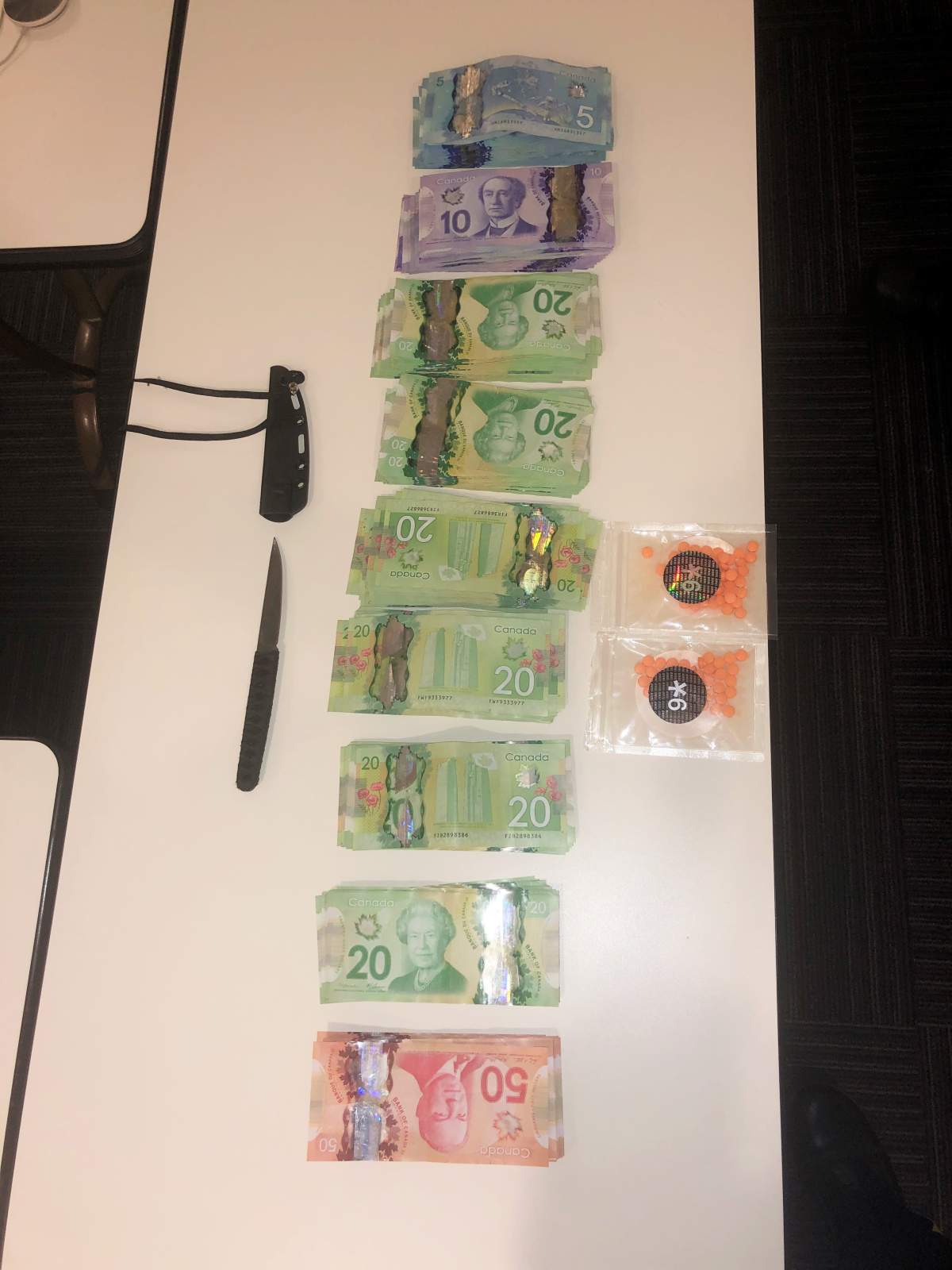 An image of the cash, pills and knife seized during the investigation at the traffic stop.