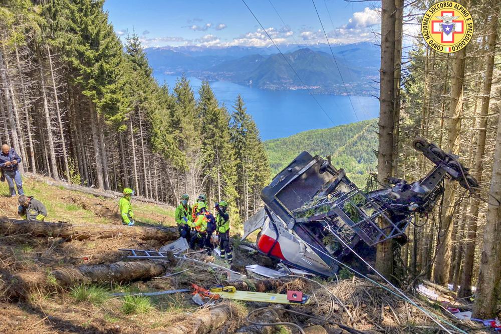 Rescuers work by the wreckage of a cable car after it collapsed near the summit of the Stresa-Mottarone line in the Piedmont region, northern Italy, Sunday, May 23, 2022. A mountaintop cable car plunged to the ground in northern Italy on Sunday, killing at least nine people and sending at least three more to the hospital, authorities said.