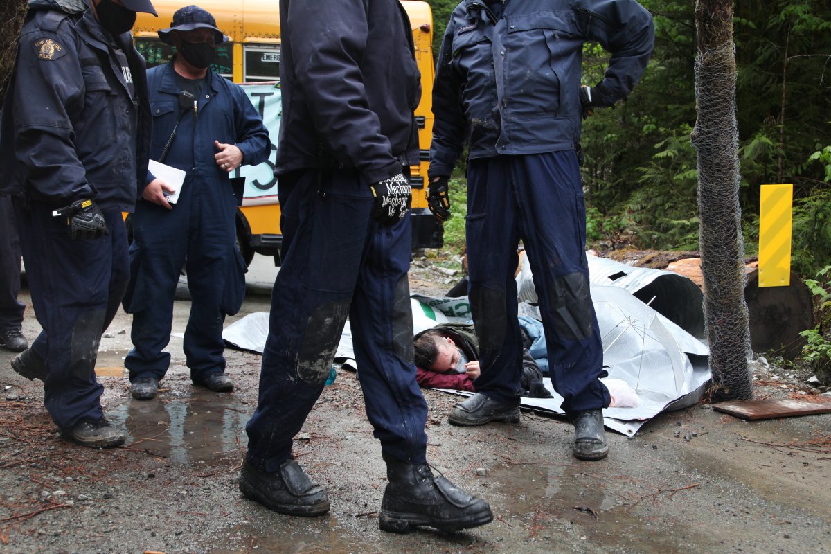 RCMP officers assess the situation as a protester lies on the ground at an anti-logging protest in Caycuse, B.C. on Tuesday, May 18, 2021. 