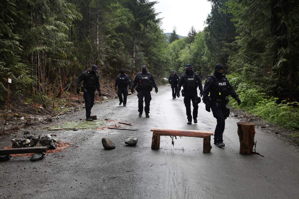 Police move obstacles out of the road at an anti-logging blockade in Caycuse, B.C. on Tuesday, May 18, 2021. 