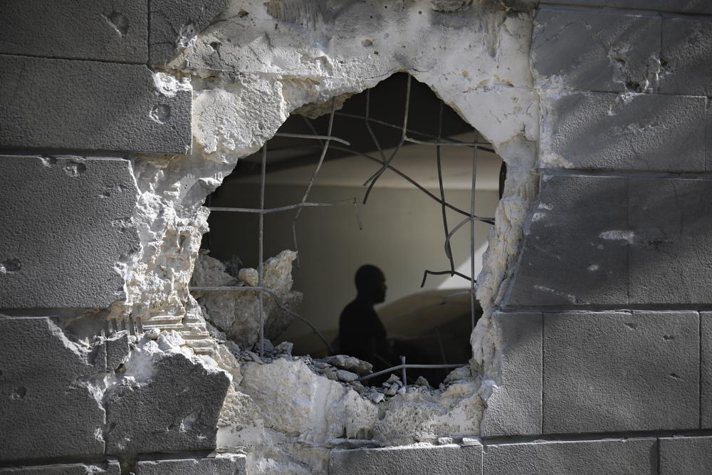 A man is seen trough a hole in a wall of a residential building after it was struck by a rocket fired from the Gaza Strip in Ashkelon, Israel, Friday, May 14, 2021.