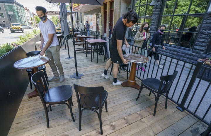 Vincent Aucoin, left, and Victor Obinot set up the patio at the Roseline Cafe in Montreal, on Thursday, May 27, 2021. Restaurant patios are set to open across Quebec on Friday. 