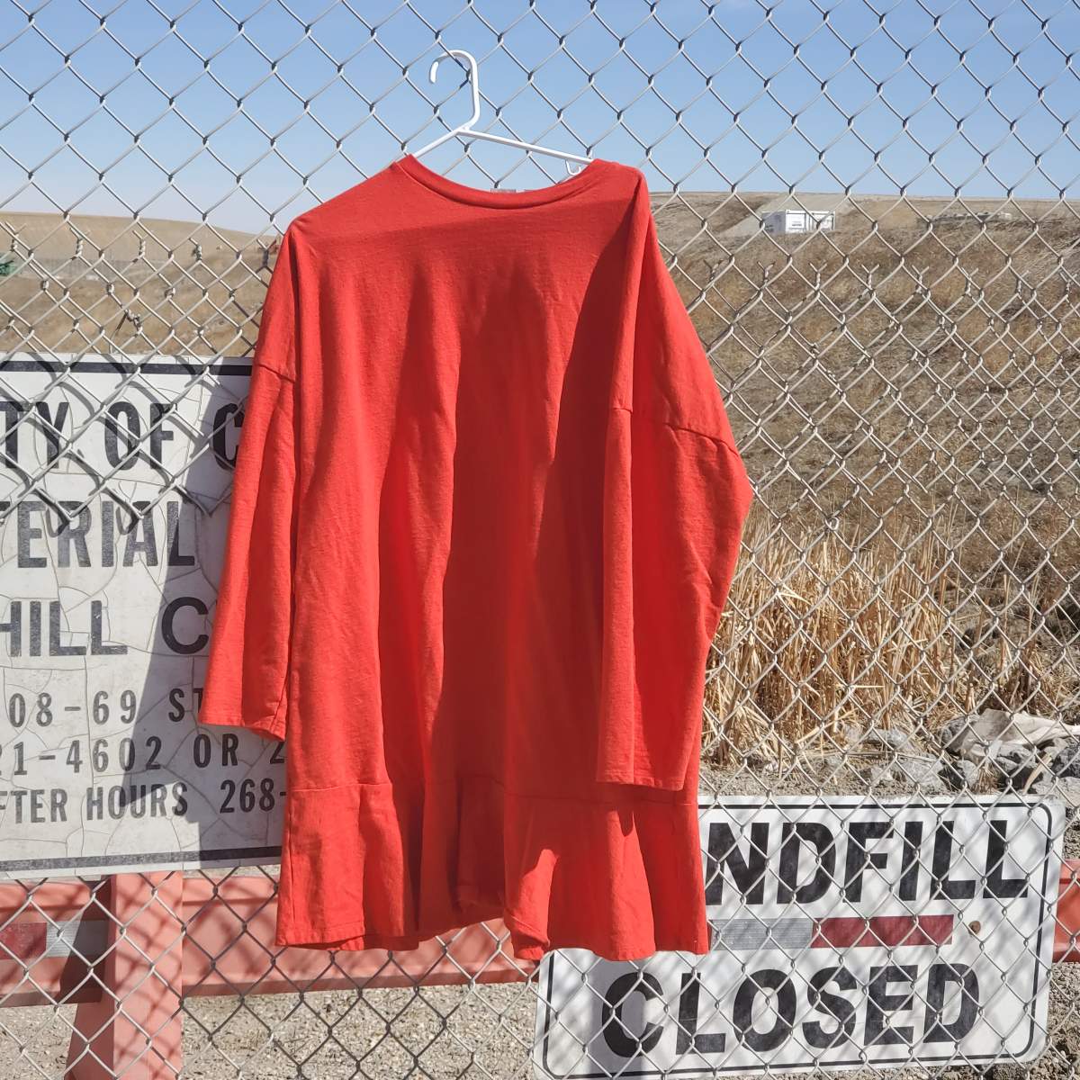 A red garment hanging on the fence of a Calgary landfill.