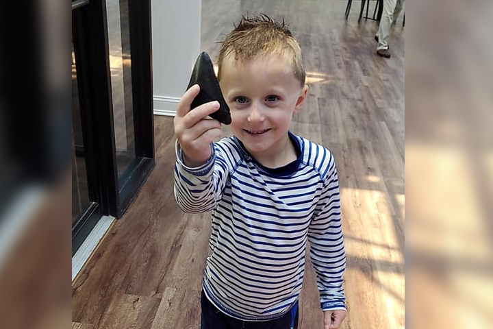 Brayden Drew, 5, shows off a megalodon shark tooth that he found in Myrtle Beach, S.C., on May 20, 2021.