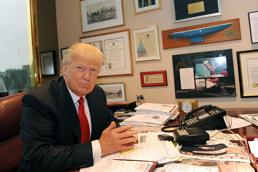 A photo of Donald Trump sitting at a desk 