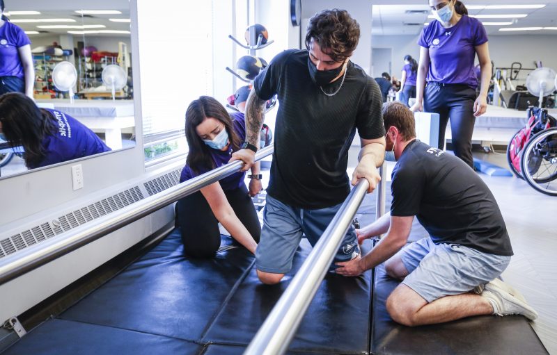 Humboldt Broncos bus crash survivor Ryan Straschnitzki, centre, is helped to move his legs by Eric Daigle, right, and Jill Mack while he attends a physiotherapy session in Calgary, Alta., Thursday, June 24, 2021.