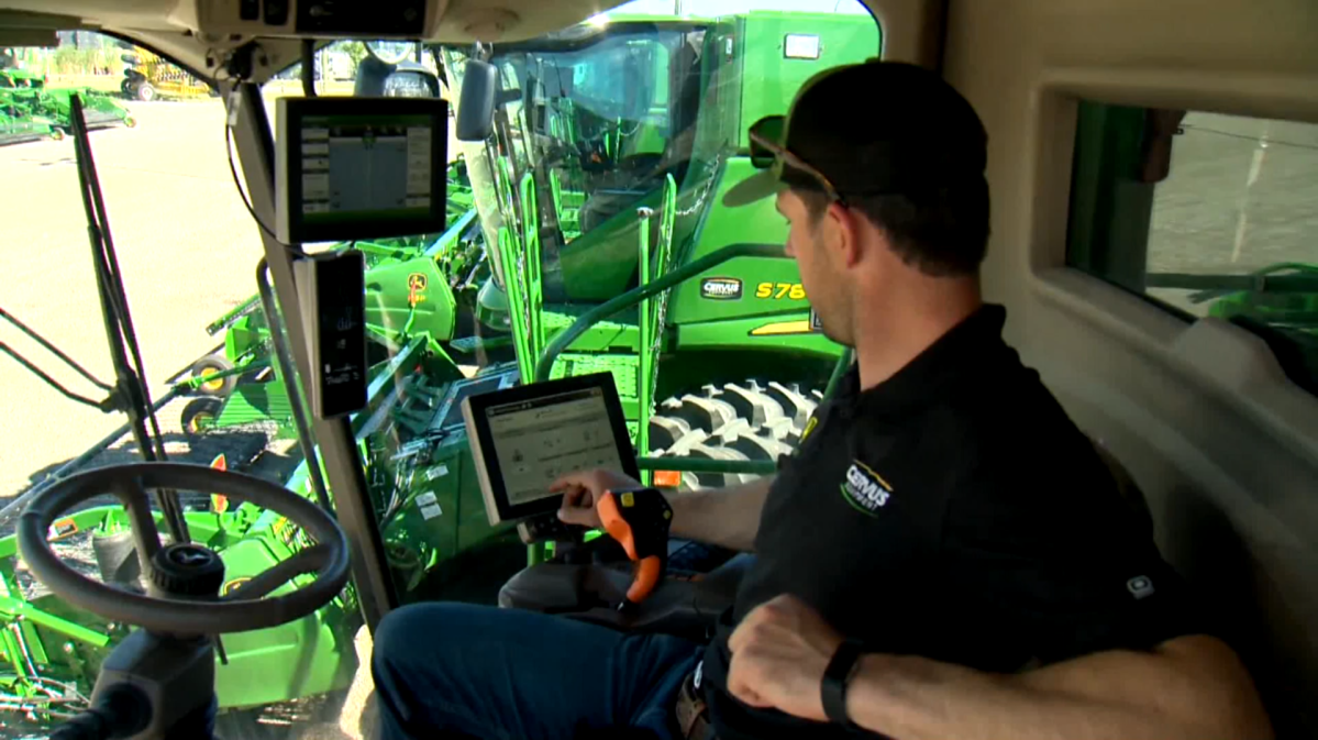 Precision Ag Specialist, Kale Scherger shows the interior of a new age John Deere combine.