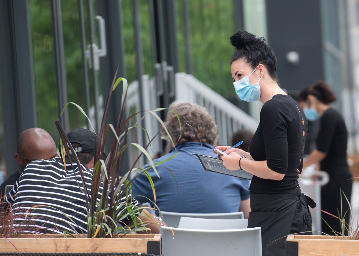 A server wears a face mask as she takes an order from a customer at a restaurant in Montreal, Saturday, June 5, 2021, as the COVID-19 pandemic continues in Canada and around the world.