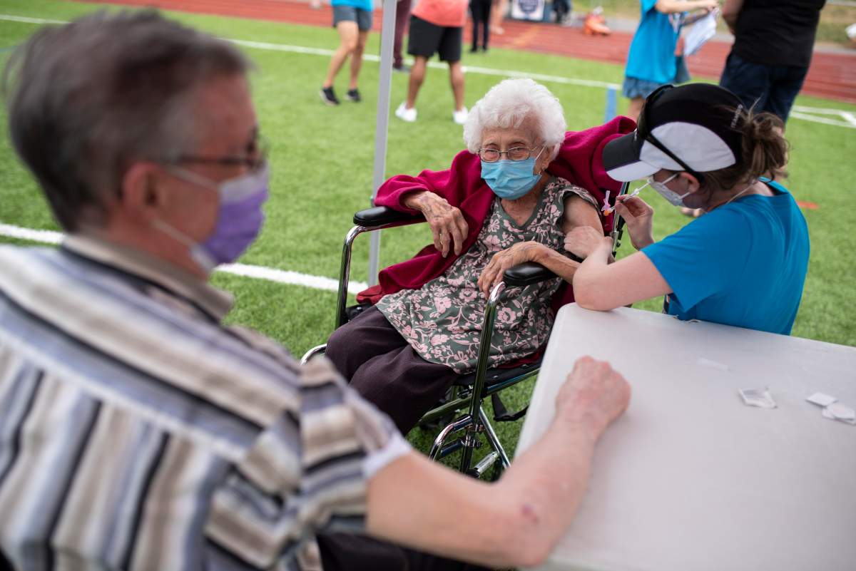 Dr. Katie Baldwin delivers a COVID-19 vaccine to Jeanne St. Onge, 101, as her husband Denis, 92, waits for his dose, at  an outdoor, pop-up vaccination clinic nicknamed "Jabapalooza" on the soccer field at Immaculata High School in Ottawa, on Saturday, June 5, 2021. 