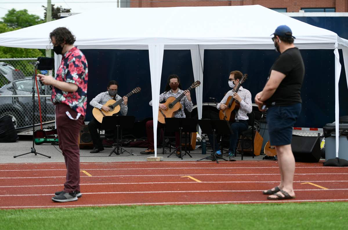 People waiting in line for their vaccines listen to the Ottawa Guitar Trio perform at an outdoor, pop-up COVID-19 vaccination clinic nicknamed 'Jabapalooza' on the soccer field at Immaculata High School in Ottawa, on Saturday, June 5, 2021.  The day marked the single-highest day in Ottawa's vaccination campaign with more than 15,000 doses administered to residents.