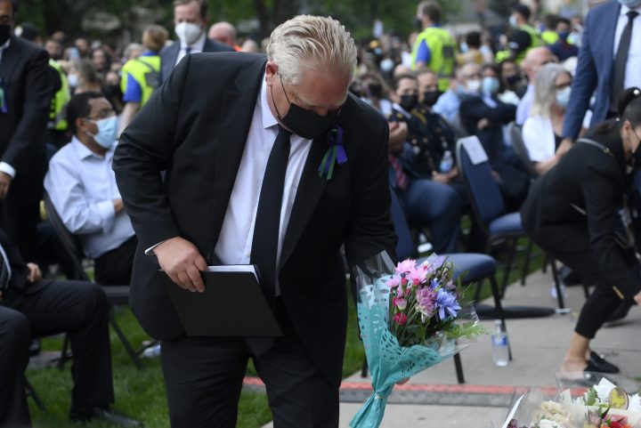 Ontario Premier Doug Ford places flowers at a vigil for the victims of the deadly vehicle attack on five members of the Canadian Muslim community in London, Ont., on Tuesday, June 8, 2021.