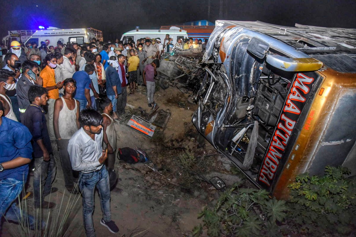 Onlookers gather near the wreckage after a bus carrying migrant workers after the lifting of coronavirus restrictions hit a delivery van on a highway near Kanpur, Uttar Pradesh state, India, Tuesday, June 8, 2021. More than a dozen people were killed. (AP Photo).