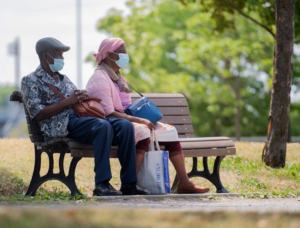 People wear face masks as they sit in a park in Montreal, Sunday, June 13, 2021, as the COVID-19 pandemic continues in Canada and around the world. 