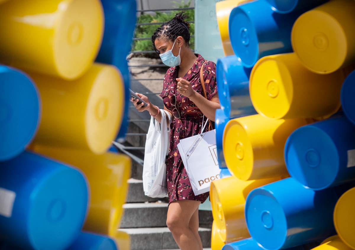 A woman wears a face mask as she walks by an art installation in Montreal, Sunday, June 13, 2021, as the COVID-19 pandemic continues in Canada and around the world. 