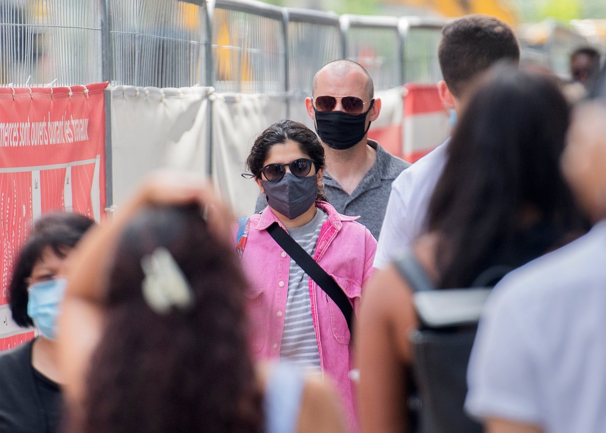 People wear face masks as they walk along a street in Montreal, Sunday, June 13, 2021, as the COVID-19 pandemic continues in Canada and around the world. 