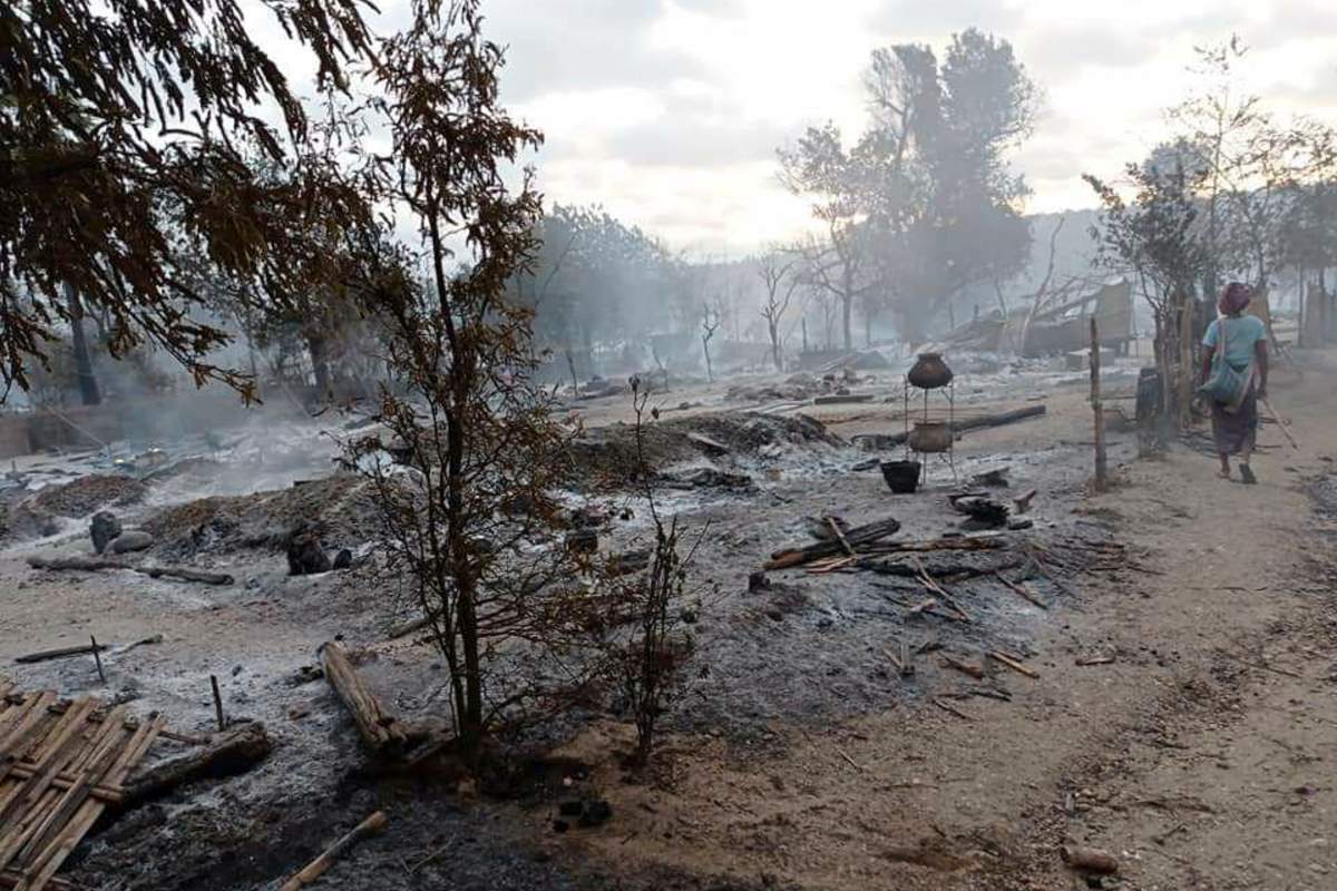 A resident walks past smoldering houses in the Kinma village, Pauk township, Magwe division, central Myanmar, Wednesday, June 16, 2021. Residents said people are missing after military troops burned the village the night before. (AP Photo).