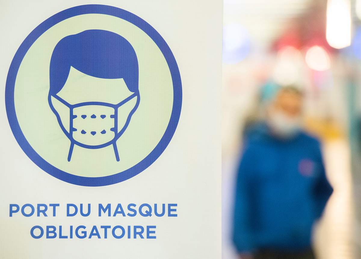 A man walks by a sign advising mandatory wearing of masks to prevent the spread of COVID-19, in Montreal, Saturday, June 19, 2021. 