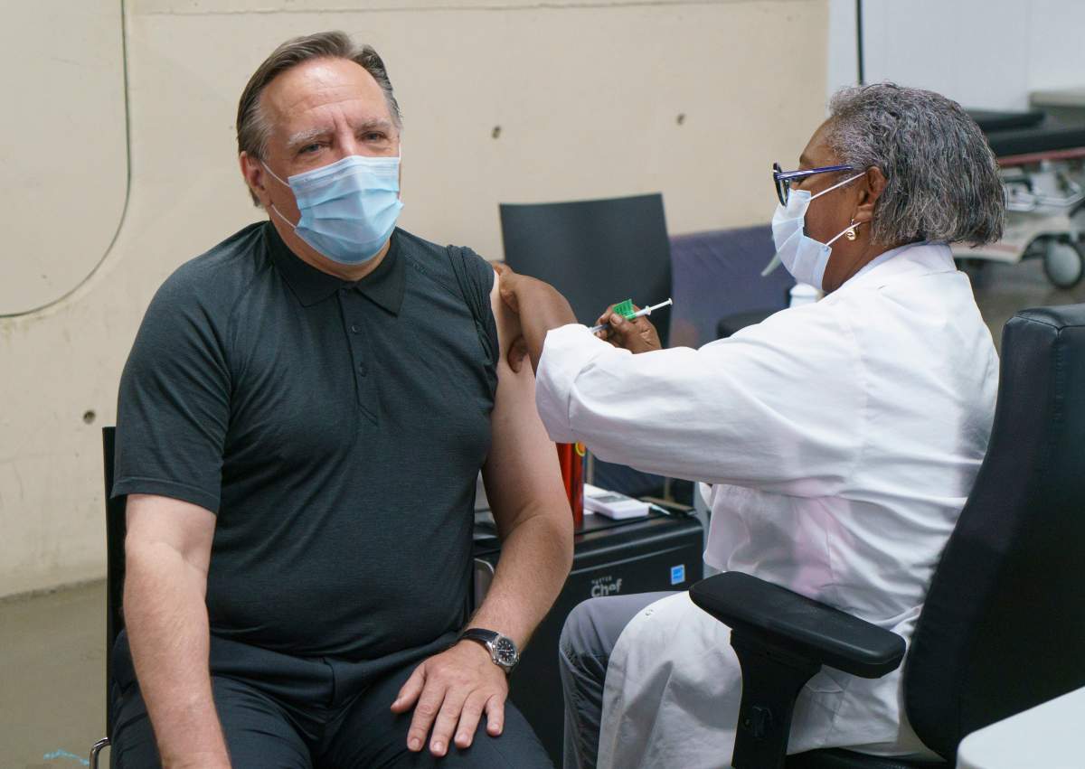 Quebec Premier François Legault receives his second dose of Pfizer vaccine from Régine Laurent, former president of the Fédération interprofessionnelle de la santé du Québec (FlQ), at a COVID-19 vaccination clinic in Montreal on Monday, June 21, 2021.