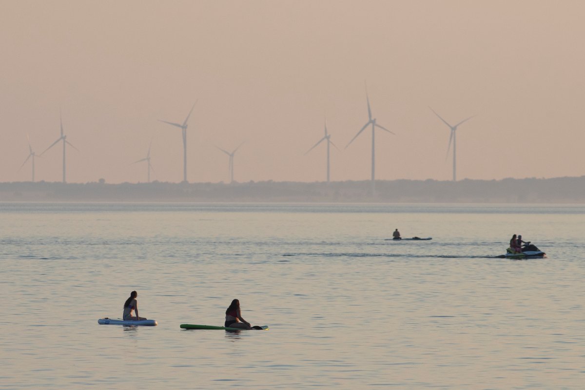 People sit on stand up paddle boards in Lake Ontario during dusk in Kingston, Ontario on July 7, 2020. 