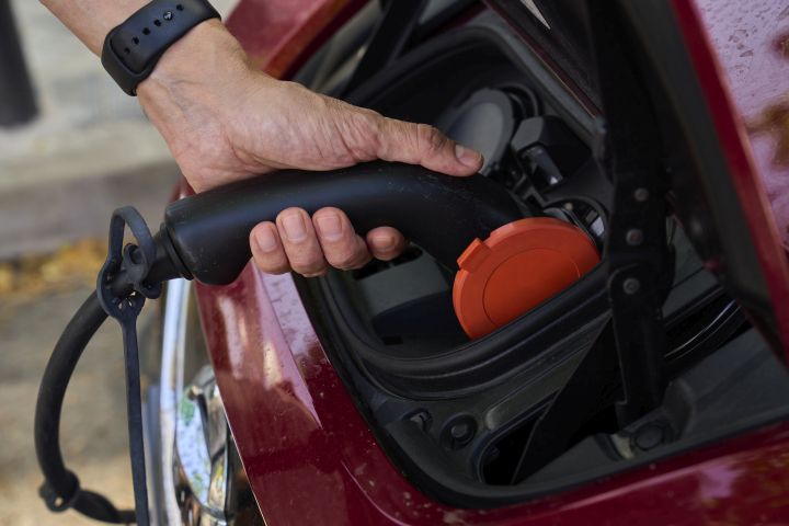 A man charges his electric car at an electrical charging point in Rivas Vaciamadrid, Spain, Tuesday, June 15, 2021.  