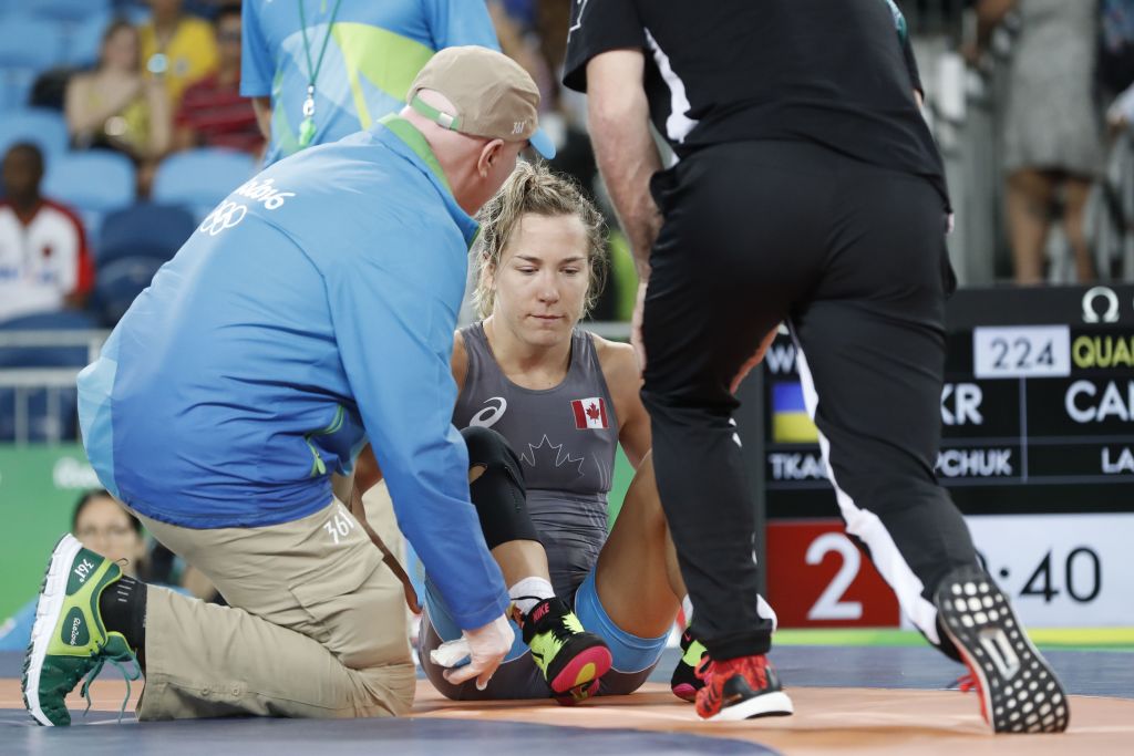 Canada’s Danielle Suzanne Lappage (blue) is treated during her fight with Ukraine’s Yuliia Tkach Ostapchuk (red) during the women’s wrestling 63kg qualifications at the Rio 2016 Olympic Games in Rio de Janeiro on August 18, 2016. AFP PHOTO Jack GUEZ