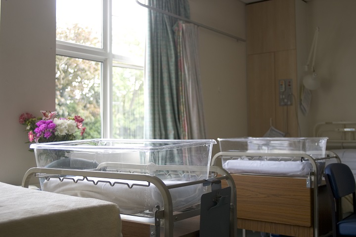 Empty baby cribs are seen in a hospital room. 