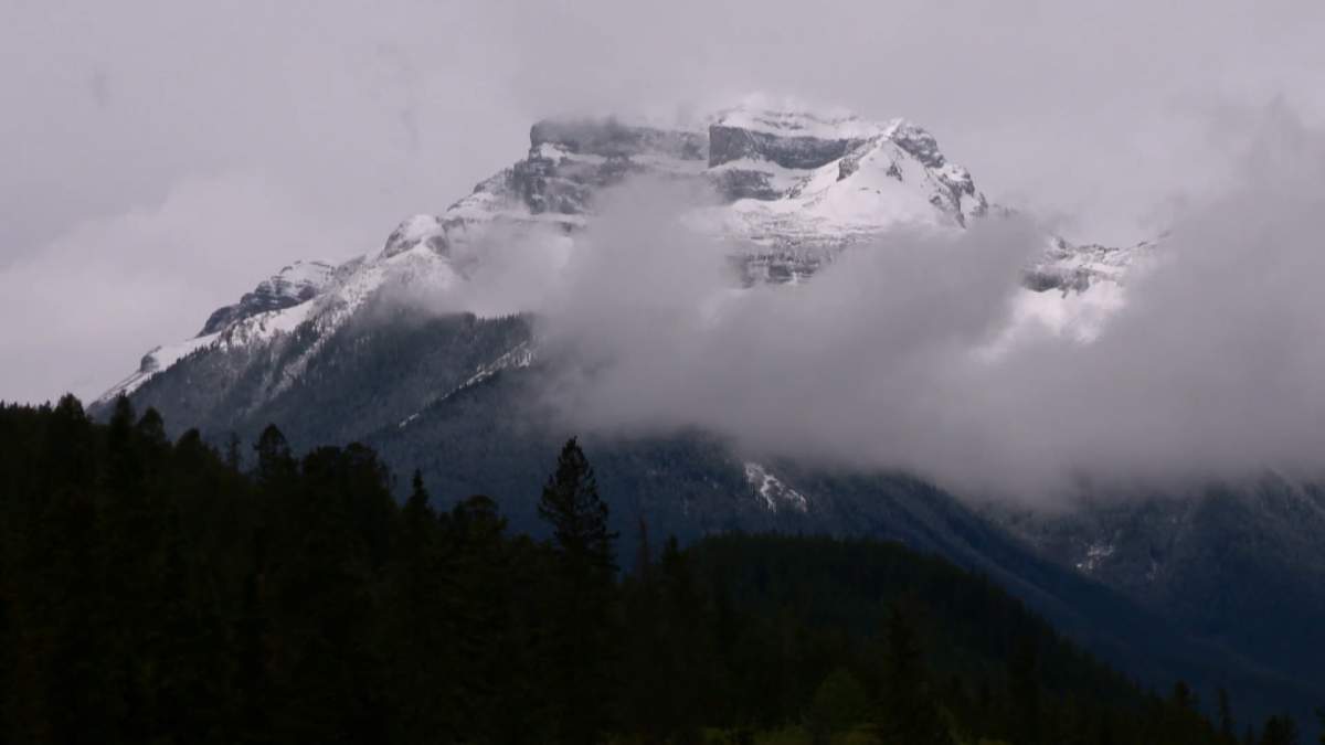 A snow-covered mountain behind clouds near Banff National Park in Canada’s Rocky Mountains.