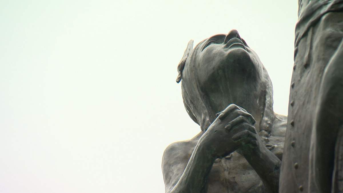 The statue depicts Hugonard embracing two children.