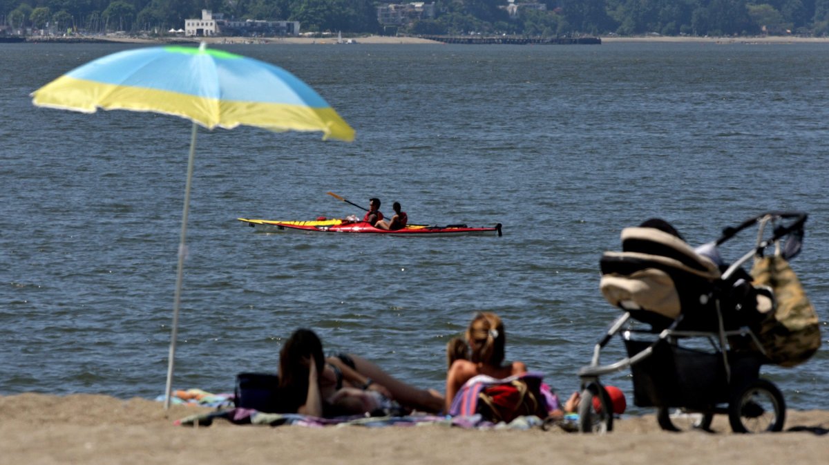 People sunbathe as kayakers pass by on the waters of English Bay in Vancouver, B.C., on Wednesday June 3, 2009. 