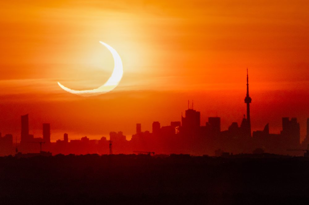 An annular solar eclipse rises over the skyline of Toronto on Thursday, June 10, 2021.