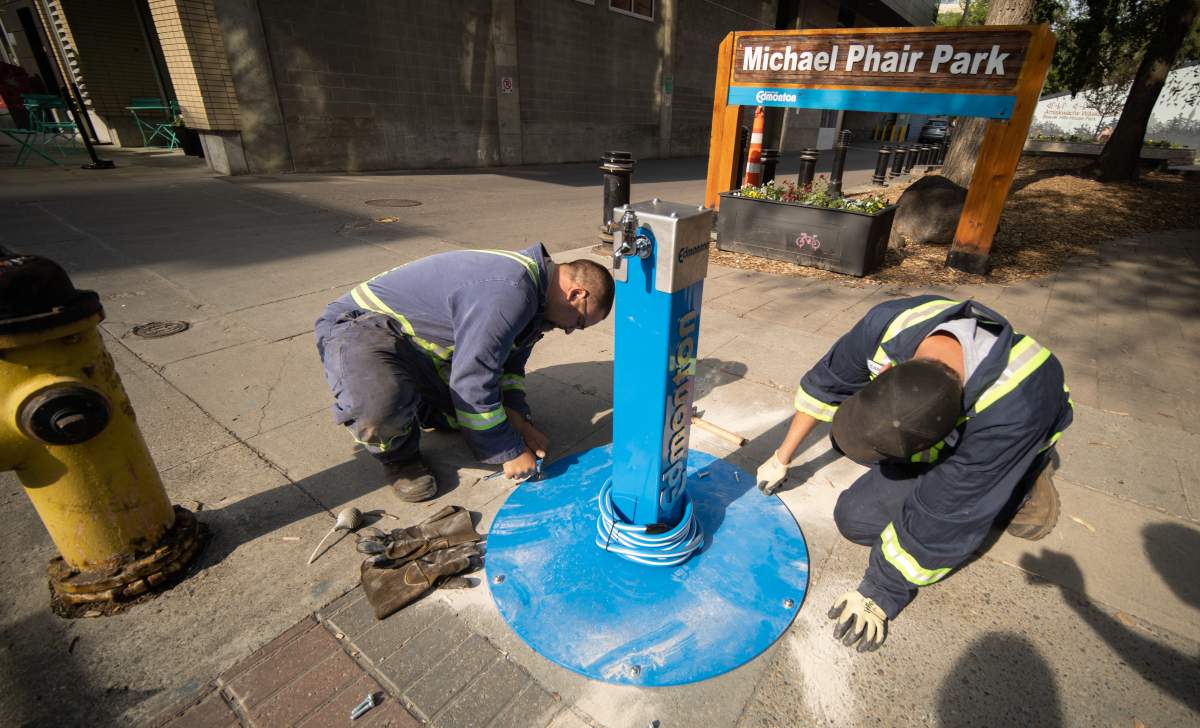 EDMONTON, ALTA: July 14, 2021 — City welders install a new outdoor water fountain beside Michael Phair Park in Edmonton on July 14, 2021. The fountains are connected to fire hydrants and allow anyone access to free, clean water.