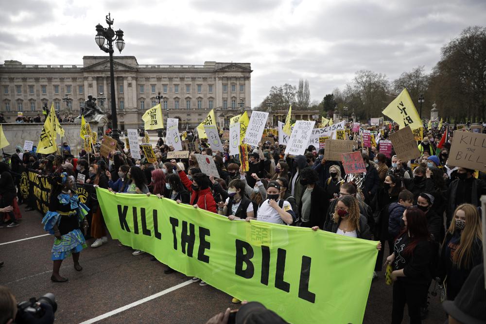 In this Saturday, April 3, 2021 file photo, demonstrators holding banners and flags march past Buckingham palace during a ‘Kill the Bill’ protest in London.