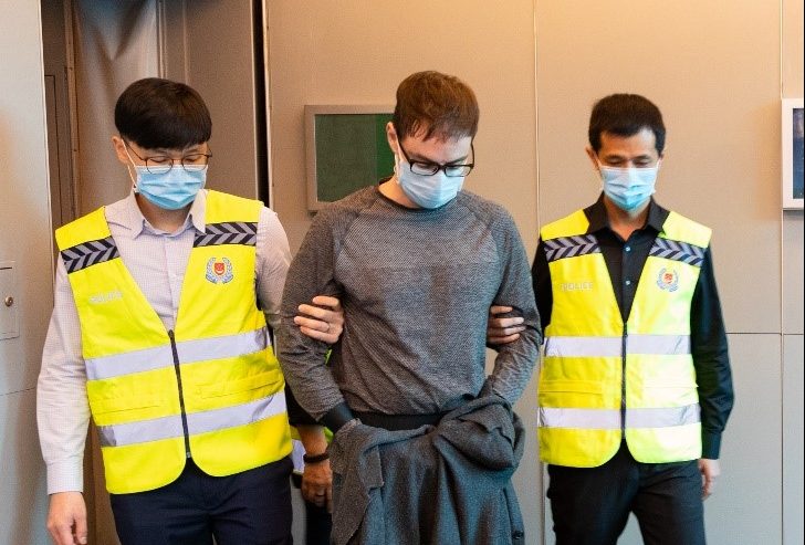 David James Roach is escorted by Singapore police officers through Singapore Changi Airport after being extradited from Britain on March 17, 2020 on charges that he robbed a bank in Singapore in 2016.