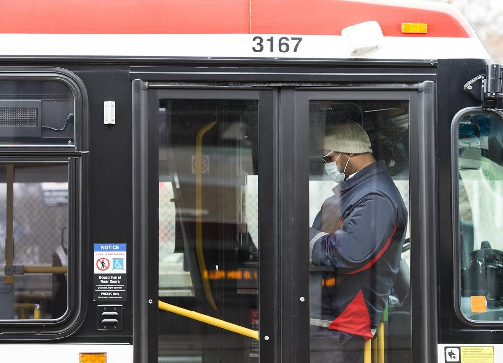 A TTC worker wears a mask in a bus while on shift in Toronto on April 23, 2020. The Toronto Transit Commission has placed a firm order for 110 low-floor transit buses with the subsidiary of NFI Group for an undisclosed price. THE CANADIAN PRESS/Nathan Denette.