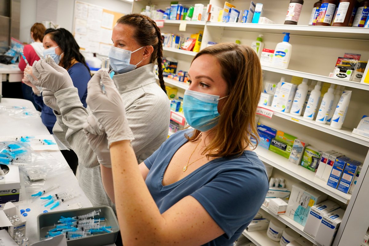 From front, registered nurses Megan McLaughlin and Amy Wells join pharmacist Claudia Corona-Guevara in drawing shots of Johnson & Johnson COVID-19 vaccine in the pharmacy of National Jewish Hospital for distribution early Saturday, March 6, 2021, in east Denver.