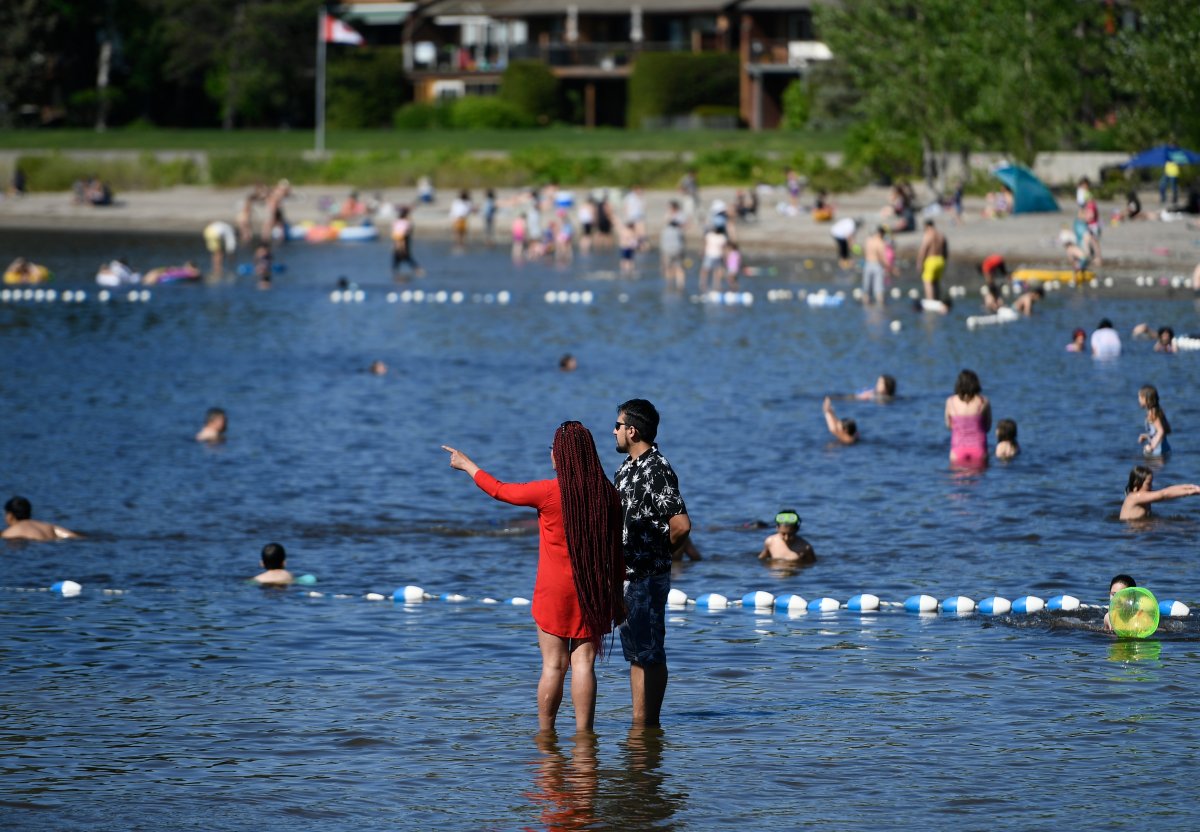 People swim in the Ottawa River as they enjoy the warm weather on the Victoria Day long weekend at Britannia Beach in Ottawa, on Monday, May 24, 2021. 
