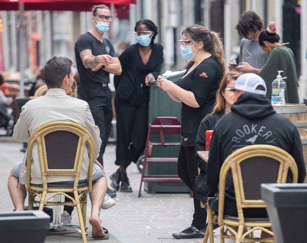 A server wears a face mask as she takes an order on a terrace at a restaurant in Old Montreal, Sunday, May 30, 2021, as the COVID-19 pandemic continues in Canada and around the world. 