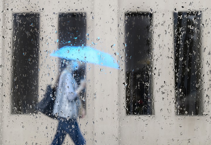 A pedestrian walks alongside businesses on a rainy day while wearing a protective mask during the COVID-19 pandemic in Toronto on Friday, June 18, 2021. THE CANADIAN PRESS/Nathan Denette.