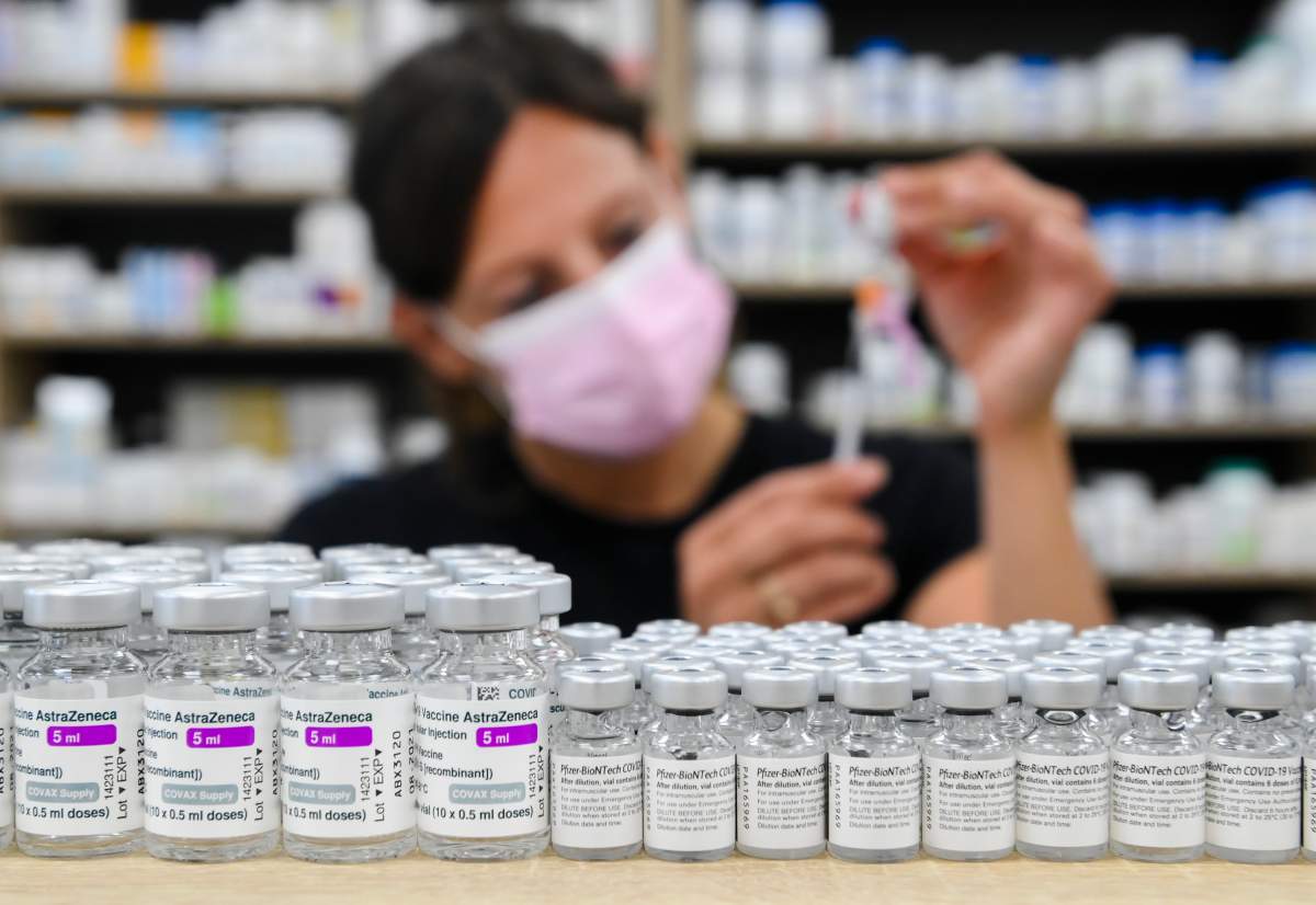 Barbara Violo, pharmacist and owner of The Junction Chemist Pharmacy, draws up a dose behind vials of both Pfizer-BioNTech and Oxford-AstraZeneca COVID-19 vaccines on the counter, in Toronto, Friday, June 18, 2021. THE CANADIAN PRESS/Nathan Denette.