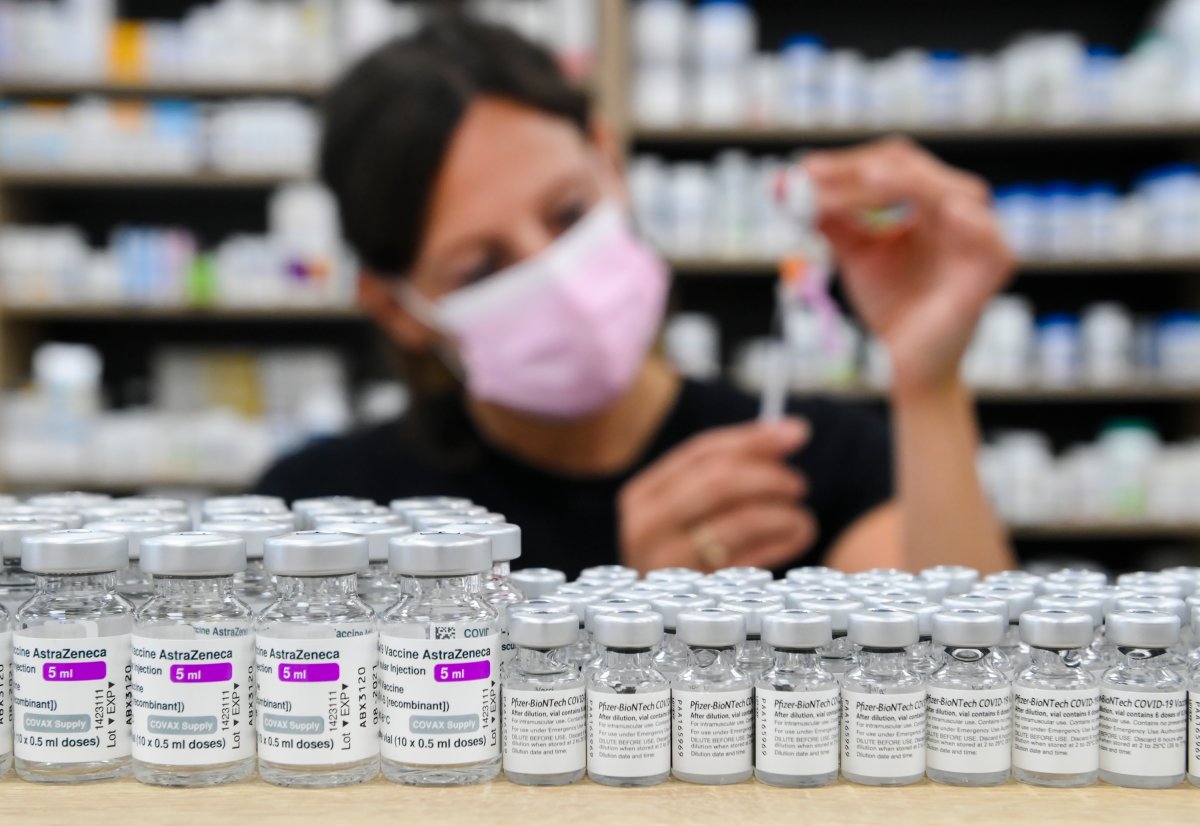 Barbara Violo, pharmacist and owner of The Junction Chemist Pharmacy, draws up a dose behind vials of both Pfizer-BioNTech and Oxford-AstraZeneca COVID-19 vaccines on the counter, in Toronto, Friday, June 18, 2021. THE CANADIAN PRESS/Nathan Denette.