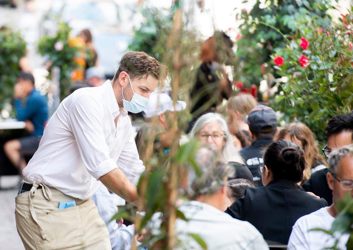 A server wears a face mask on an outdoor terrace at a restaurant in Old Montreal, Sunday, July 4, 2021, as the COVID-19 pandemic continues in Canada and around the world. 