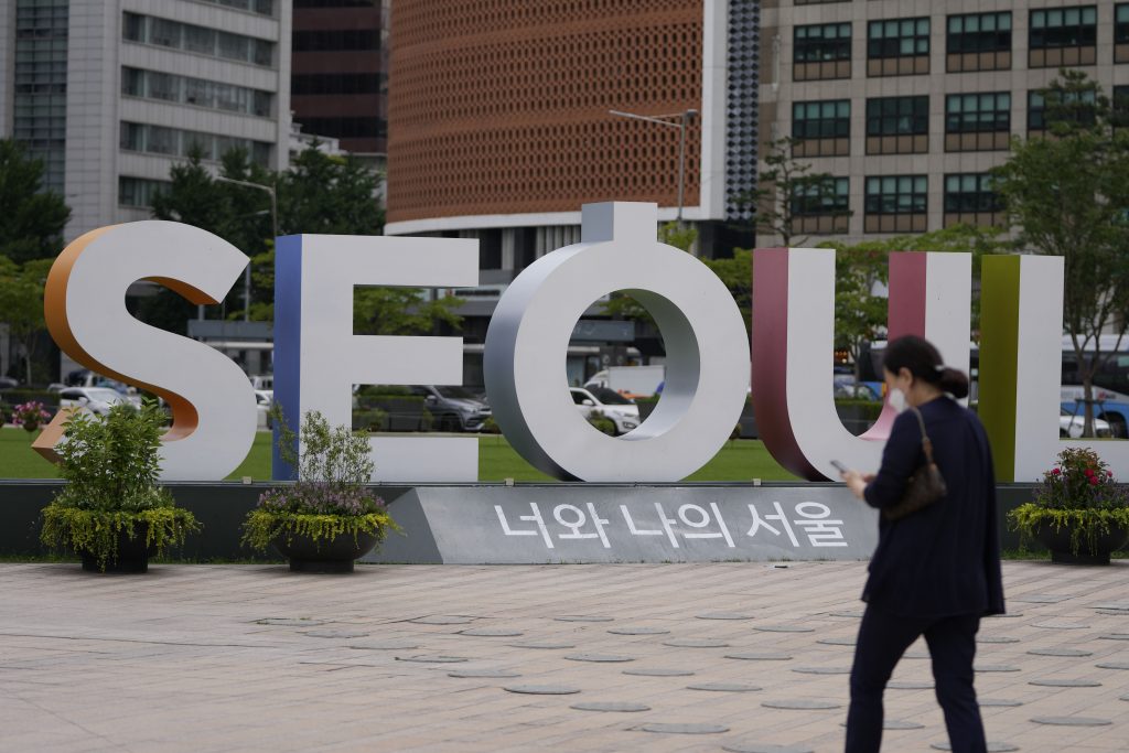 A woman wearing a face mask to help curb the spread of the coronavirus walks near the display of the Seoul logo in Seoul, South Korea, Wednesday, July 7, 2021. South Korea is seeing a steep rise in coronavirus infections unseen since the worst of its outbreak last winter as it slips into another surge while most of its people are still unvaccinated. (AP Photo/Lee Jin-man).