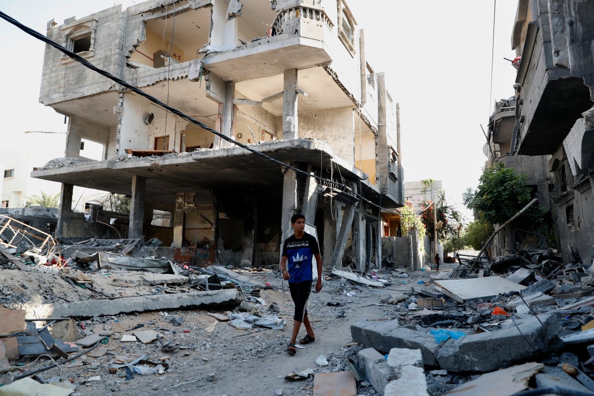 A Palestinian youth walks among the rubble of a building that collapsed after it was hit by airstrikes during an 11-day war between Gaza's Hamas rulers and Israel last May, in the Maghazi Refugee Camp, central Gaza Strip, Monday, July 12, 2021.