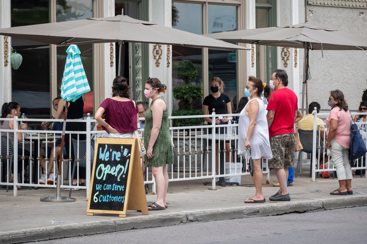 People wear masks to protect them from the COVID-19 virus while waiting to be seated at a restaurant patio in Kingston, Ontario on Tuesday July 13, 2021. THE CANADIAN PRESS IMAGES/Lars Hagberg.