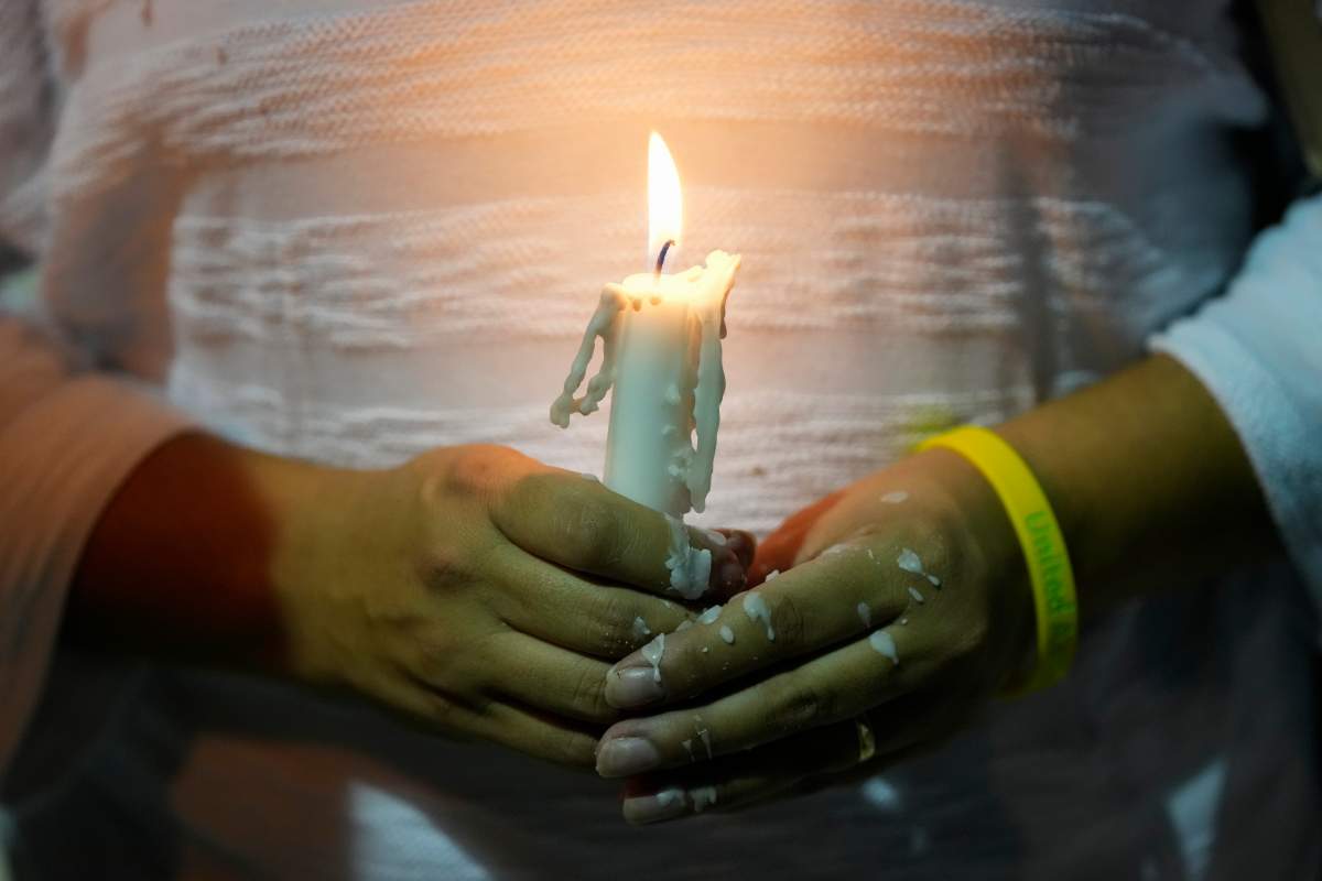 Dislamy Pelayo holds a candle during a multi-faith vigil for victims of the Champlain Towers South condo building collapse, near the site where the building once stood, Thursday, July 15, 2021, in Surfside, Fla.